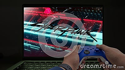 Playing Cyberpunk 2077 on a computer with a blue xbox controller Editorial Stock Photo