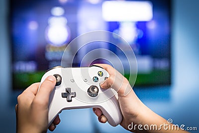 Video gaming and game play on tv fun gamer holding game-pad and controller video console playing and enjoying with blurred screen Editorial Stock Photo