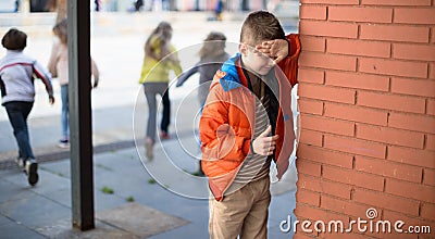 playing hide and seek. boy closed eyes his hands standing at brick wall Stock Photo