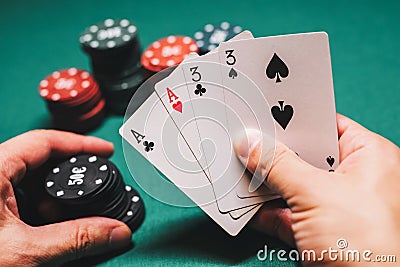 Playing poker in the casino. Cards with two pairs in the hand of the player making a bet with chips Stock Photo