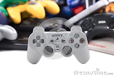 A Playstation Controller in front of a Pile of Retro Game Controllers Editorial Stock Photo