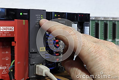 PLC - Programmable logic controller. Production automation. The hand points to the indicator LED. Stock Photo