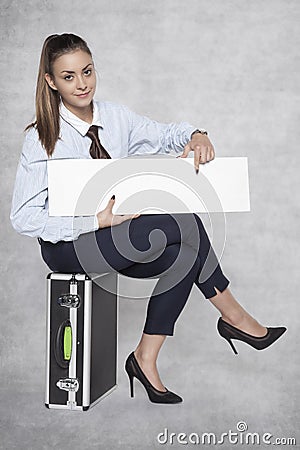 pleasant business woman sits on a suitcase and holds a commercial on her knees Stock Photo