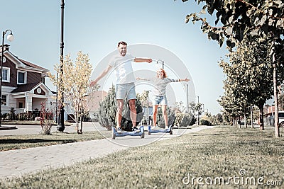 Pleasant cheerful couple shaking hands riding on the self-balancing scooter. Stock Photo