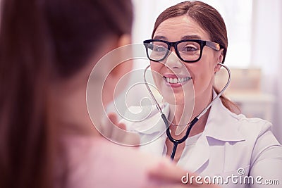 Pleasant cheerful general practitioner wearing glasses examining cute girl Stock Photo