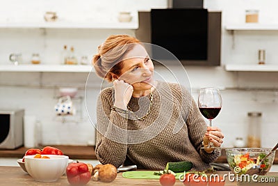 Pleasant ginger mature woman wearing sweater while staying in kitchen alone Stock Photo