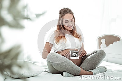 Pleasant happy future mother observing photo result of ultrasound procedure Stock Photo