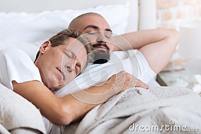 Pleasant non-traditional couple sleeping in the one bed Stock Photo