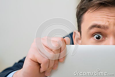 Pleasant office worker hiding behind laptop Stock Photo