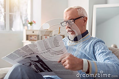 Pleasant senior man reading article in the newspaper Stock Photo