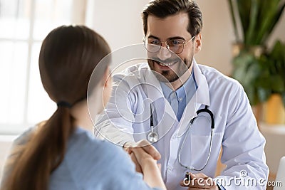 Pleasant smiling male doctor meeting young woman patient at clinic Stock Photo