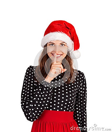 Pleasant woman keeps finger on lips, asks not tell secret information or keep silence. emotional girl in santa claus christmas hat Stock Photo