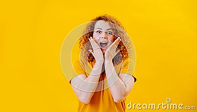 Pleasantly surprised young woman with curly hair standing with gaping mouth Stock Photo