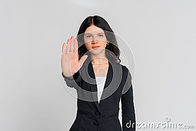 Please, do not, stop. Young serious dark-haired girl, who is looking in the camera and extends arm in stop sign, standing over Stock Photo