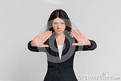 Please, do not, stop. Young serious dark-haired girl, who is looking in the camera and extends palms in stop sign, standing over Stock Photo