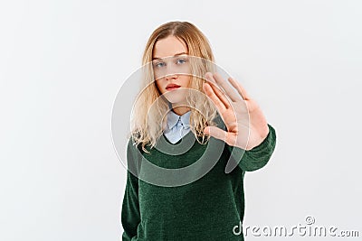 Please, do not, stop. Young serious woman in casual clothes, who is looking in the camera and extends arm in stop sign. Social Stock Photo