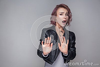 Please don`t touch me. Portrait scared of beautiful girl with short hairstyle in casual style black leather jacket standing, Stock Photo