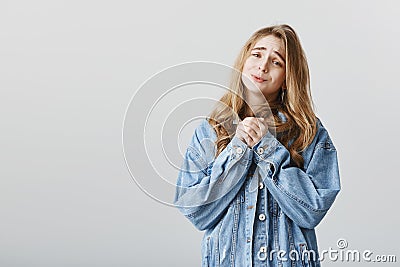 Please, one more offer honey. Portrait of cute european female student with blond hair in denim jacket, clenching hands Stock Photo