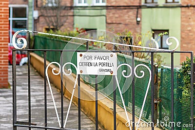 Please Shut The Gate. Thanks. Spanish sign on a metal courtyard ornament iron door Stock Photo