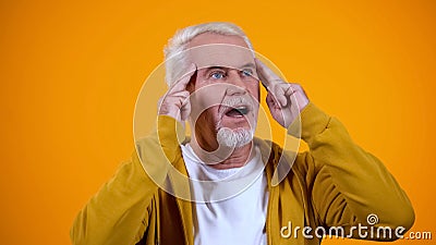 Pleased aged magician touching temples, developing telepathic mind abilities Stock Photo