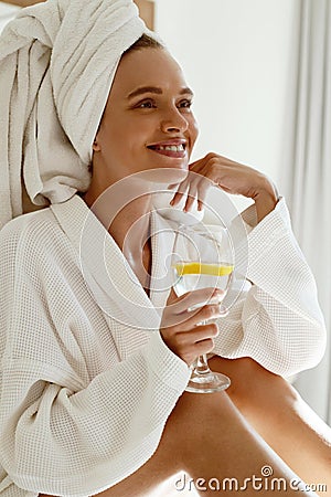 Pleased european girl drink lemonade in bathrobe Stock Photo