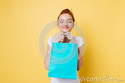Pleased ginger woman holding packet in hands with closed eyes Stock Photo