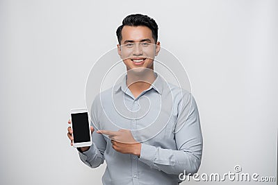 Pleased happy young asian man holding smartphone pointing at cellphone screen as showing awesome new phone Stock Photo