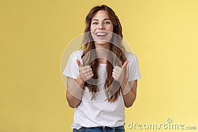 Pleased outgoing cheerful good-looking caucasian girl curly long haircut white t-shirt show thumbs up smiling lively Stock Photo