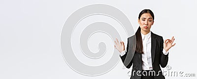 Pleased sassy asian businesswoman in black suit show not bad gesture, nod in approval and make okay gesture, very good Stock Photo