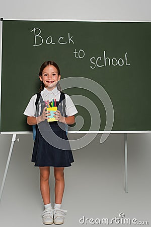 pleased schoolkid holding pen holder near Stock Photo