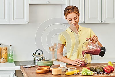 pleased woman pouring delicious smoothie from Stock Photo