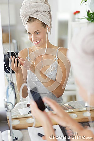 pleased woman with towel on head messaging with phone Stock Photo