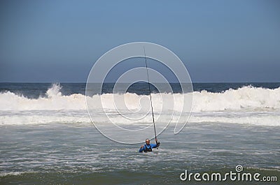 A Fisher stands in the water, in front of huge waves of the wild Indian ocean. South Africa. Editorial Stock Photo
