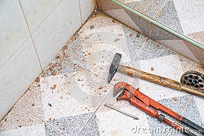 Plier, small hammer and neil on the restroom ground, with the dust from reparing in for broken pipe Stock Photo