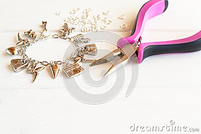 Pliers, bracelet, metal ring on a white wooden background. How to make yourself metal bracelet Stock Photo