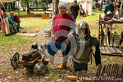 Ploiesti, Romania - July 14, 2018: Actor dressed up ottoman turk warrior poses surrounded by medieval weapons, cannon, swords and Editorial Stock Photo