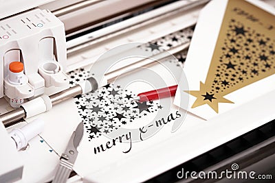 plotting machine makes large christmas stickers with star symbols and lettering from black adhesive vinyl film. Stock Photo