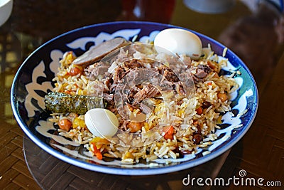 Plov pilaf plate on black background. Traditional Uzbek cuisine. Rice prepared with vegetables and meat Stock Photo