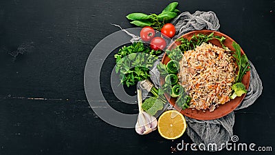 Plov Rice with meat and vegetables on a plate. Uzbek cuisine. On a wooden background. Top view. Stock Photo