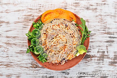 Plov Rice with meat and vegetables on a plate. Uzbek cuisine. On a wooden background. Top view Stock Photo