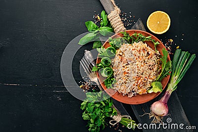 Plov Rice with meat and vegetables on a plate. Uzbek cuisine. On a wooden background. Top view Stock Photo