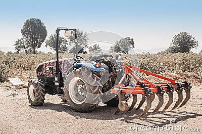 Plow for cultivating the soil is attached to a dusty tractor. Equipment in industry of Editorial Stock Photo