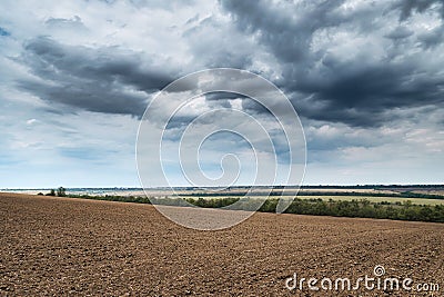 Plowed field and dramatic blue sky, soil and clouds of a bright sunny day - concept of agriculture Stock Photo