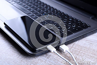 Plug in USB cord,cable charger,charging,charged and data transfer of the mobile phone,smartphone with a laptop on wooden floor, Stock Photo