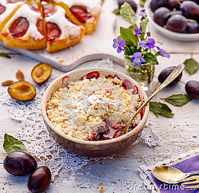 Plum Crumble, stewed plums topped with crumble of flour, butter and sugar in a baking dish on a wooden table. Stock Photo