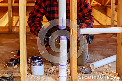 Plumber applying glue to PVC pipe under construction in new home Stock Photo