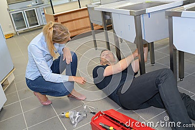 Plumber carries out repair work in kitchen Stock Photo