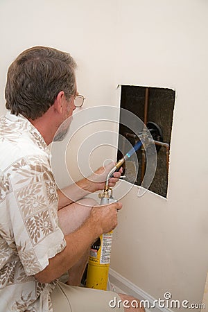 Plumber cutting access hole Stock Photo