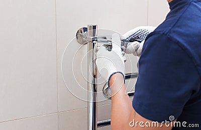 Plumber fixing chrome heated towel rail in bathroom Stock Photo