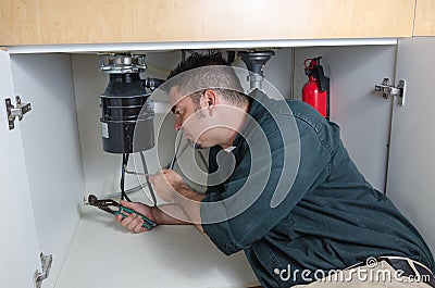 Plumber fixing a garbage disposal Stock Photo